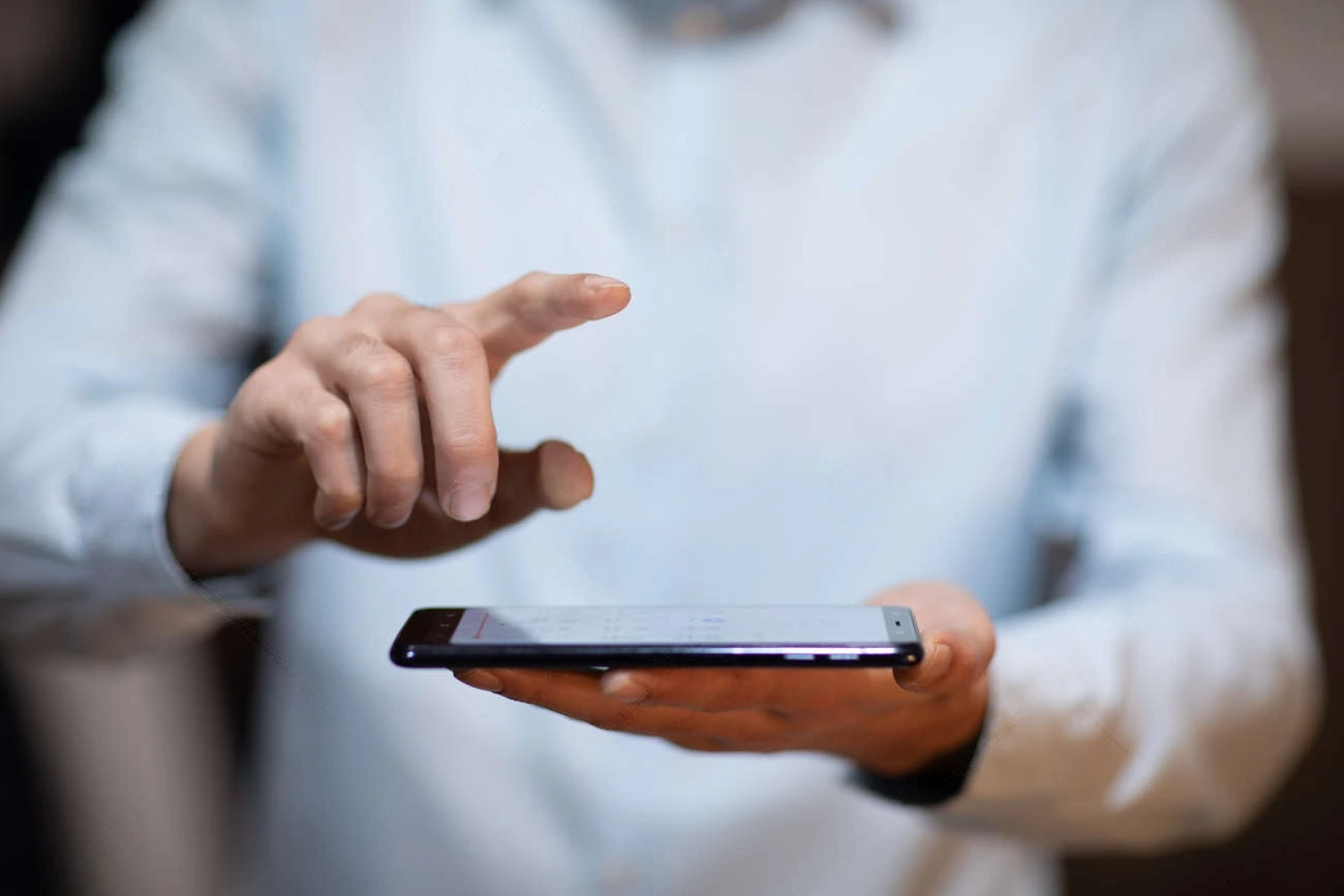 A person in a light blue shirt holds a smartphone in one hand, using the other to scroll through catchy IG Captions on the screen.
