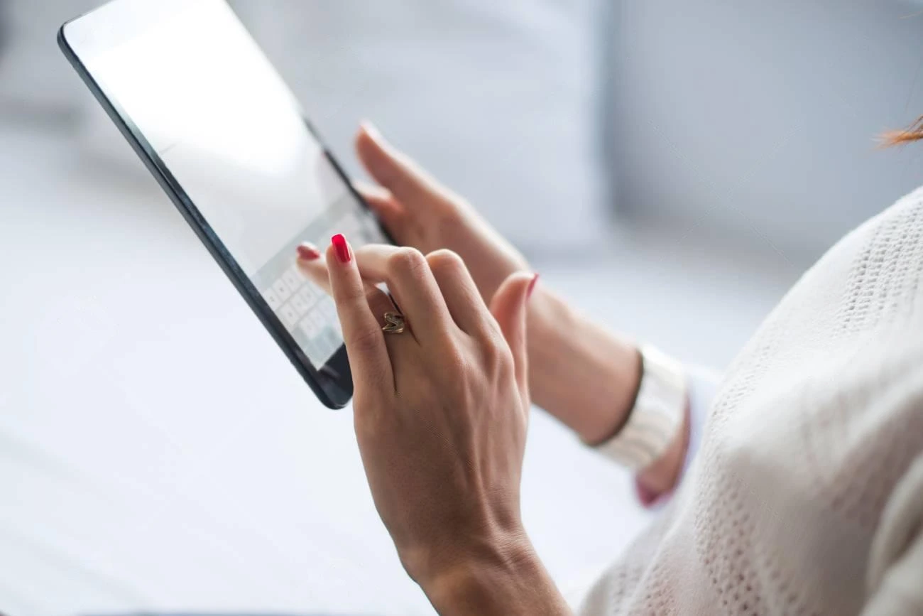 A person wearing a white sweater uses a tablet, typing on the on-screen keyboard with well-manicured hands while checking their Instagram Story Views.