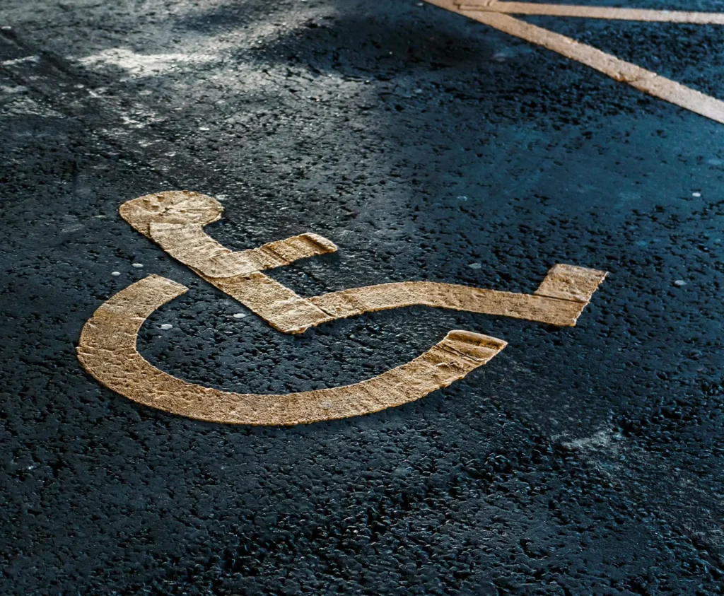Yellow disabled parking symbol painted on an asphalt surface, indicating a reserved parking space for persons with disabilities and promoting digital accessibility in public spaces.
